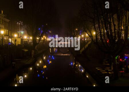 In Utrechter, Niederlande, 21. Januar 2020. Doppelbogensteinbrücke über den Kanal im Zentrum von Utrechter. Nebliger Abend, Blick auf den Kanal, Häuser Stockfoto