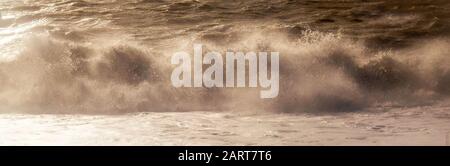 Eine weiße Spraylinie, die den dramatischen Moment erfasst, in dem eine Welle in einem stürmischen Meer bricht, das weißes Spray und Wellen hoch in die Luft, Bewegung und B. sendet Stockfoto