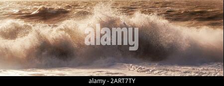 Eine weiße Spraylinie, die den dramatischen Moment erfasst, in dem eine Welle in einem stürmischen Meer bricht, das weißes Spray und Wellen hoch in die Luft, Bewegung und B. sendet Stockfoto