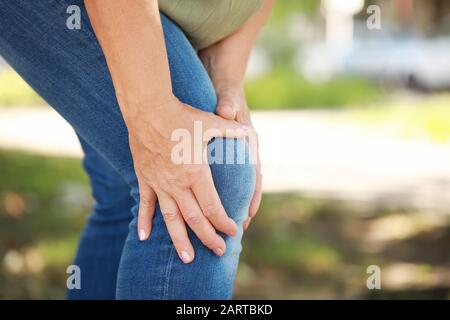 Reife Frau, die im Freien unter Schmerzen im Knie leidet, Nahaufnahme Stockfoto