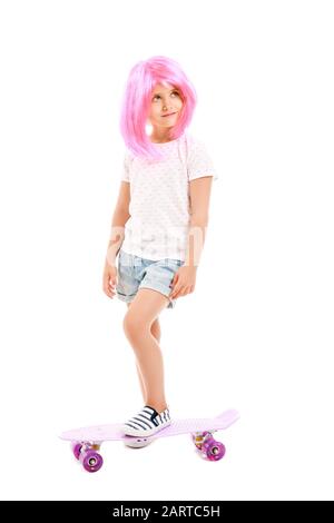 Süßes kleines Mädchen in Perücke und mit Skateboard auf weißem Hintergrund Stockfoto