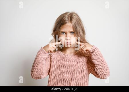 Grimmiges kleines Mädchen auf hellem Hintergrund Stockfoto