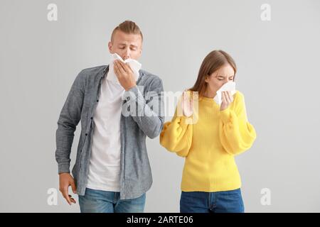 Junge Paare, die an Allergie auf hellem Hintergrund leiden Stockfoto