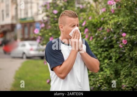 Junger Mann, der im Freien an Allergie leidet Stockfoto