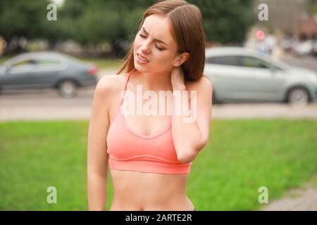 Junge sportliche Frau leidet im Freien unter Nackenschmerzen Stockfoto