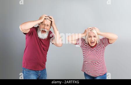 Wütend reifes Paar auf grauem Hintergrund Stockfoto