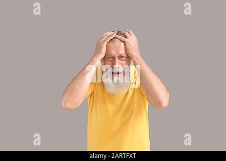 Wütend reifer Mann auf grauem Hintergrund Stockfoto