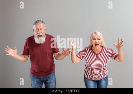 Wütend reifes Paar auf grauem Hintergrund Stockfoto