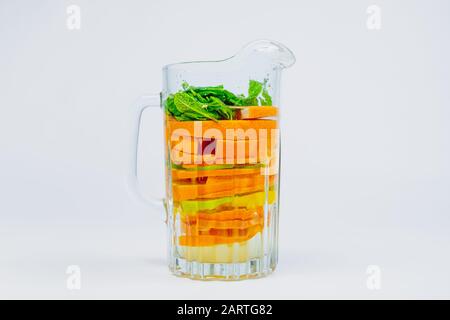 Großer Glasbecher mit Zitrusfrüchten und Minze im weißen Hintergrund. Limonade mit Orangen, Kalk und Zitronen. Gesundes und vitaminreiches Fruchtgetränk Stockfoto