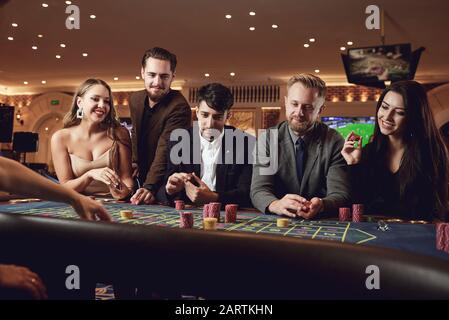 Eine Gruppe junger lächelnder Leute spielt Roulette in einem Casino. Stockfoto