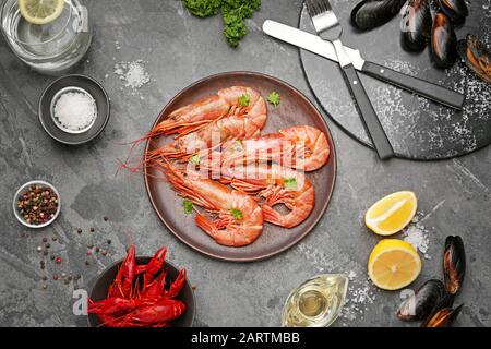 Teller mit leckeren Garnelen, Krebsen und Muscheln auf grauem Hintergrund Stockfoto