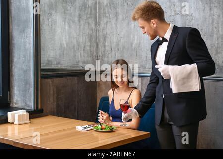 Kellner bringt Wein für junge Frau ins Restaurant Stockfoto