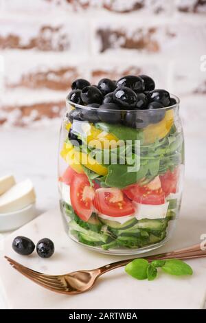 Glas mit leckerem griechischen Salat auf dem Tisch Stockfoto