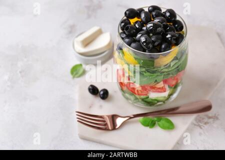 Glas mit leckerem griechischen Salat auf dem Tisch Stockfoto