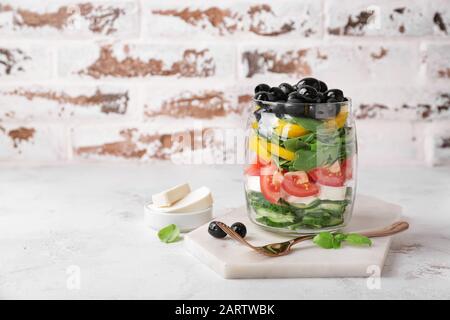 Glas mit leckerem griechischen Salat auf dem Tisch Stockfoto