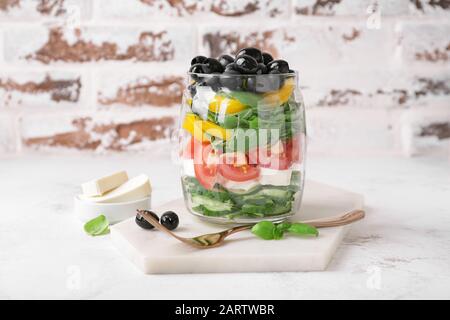 Glas mit leckerem griechischen Salat auf dem Tisch Stockfoto