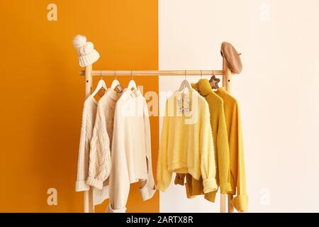 Rack mit Winterkleidung auf Farbhintergrund Stockfoto