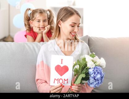 Schöne junge Frau mit Geschenken von ihrer Tochter zu Hause Stockfoto