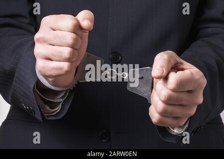Handschellen an den Händen eines Büroangestellten, Nahaufnahme. Haftkonzept Stockfoto