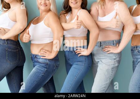 Gruppe körperpositiver Frauen, die Daumenaufschlag auf Farbhintergrund zeigen Stockfoto