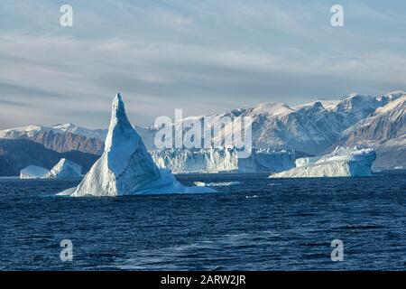 Sonnenaufgang im Fjord Scoresby Sund. Schwimmende Eisberge vor verschneiten Bergen. Kangertitittivaq, Grönland, Dänemark Stockfoto