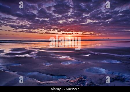 Sonnenaufgang am Strand von Bamburgh mit Blick auf die Farne Islands, Bamburgh, Northumberland, england, Großbritannien Stockfoto