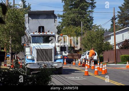 Kipper, Bagger und Arbeiter. Straßenbauarbeiten. Austausch der Asphaltstraßenoberfläche. Stockfoto