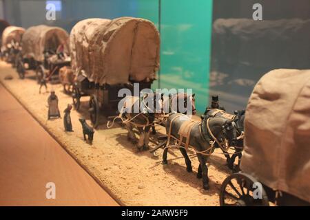 Miniaturkonvoi mit Pferdewagen und Figuren von Menschen. Die ersten Europäer entdecken Amerika. Geräusche und großes Getreide - Stilisierung unter dem Film. Also Stockfoto