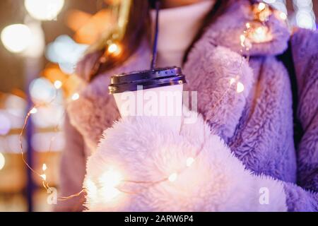 Mädchen hält Pappglas mit Kaffee oder heißem Tee im Winter in warmen Fäusten Stockfoto