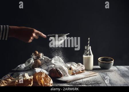 Frau streut Zuckerpulver auf den Tisch Stockfoto