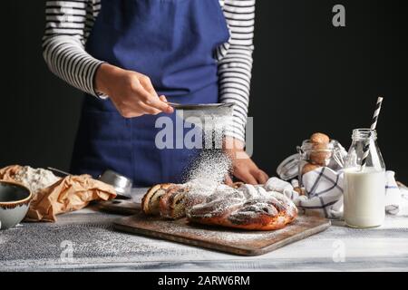 Frau streut Zuckerpulver auf den Tisch Stockfoto