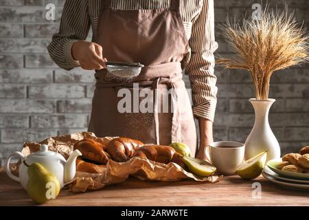 Frau streut in der Küche Zuckerpulver auf Crescents Stockfoto