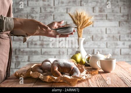 Frau streut in der Küche Zuckerpulver auf Crescents Stockfoto