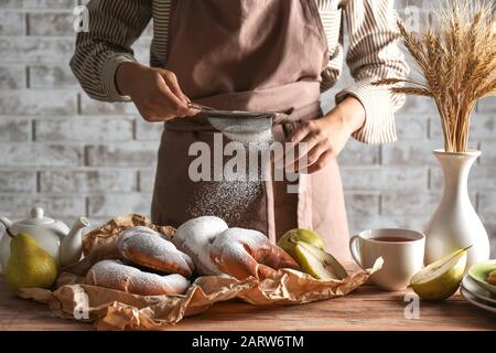 Frau streut in der Küche Zuckerpulver auf Crescents Stockfoto