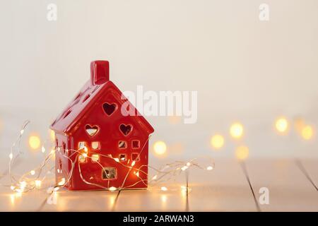 Kleines Haus mit glühender Girlande auf weißem Tisch Stockfoto