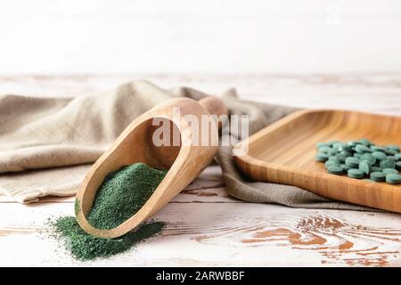 Mit Spirulina-Pulver und Pillen auf Holzhintergrund schaufeln Stockfoto