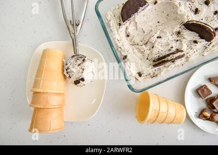 Leckere Eiscreme mit Wafer-Tassen, Plätzchen und Schokolade auf weißem Hintergrund Stockfoto