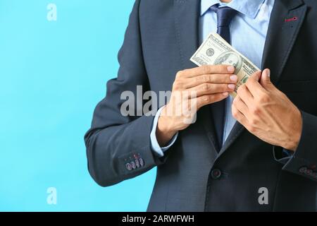 Geschäftsmann, der Bestechung vor Farbhintergrund in die Tasche steckt. Konzept der Korruption Stockfoto