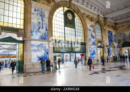 Porto, Portugal - Jan 10, 2020: Einrichtung von Sao Bento Bahnhof mit typischen Azulejo Kacheln. Typisch portugiesischen Kacheln Azulejos, der Bahnhof ist UNESCO-Weltkulturerbe. Die Leute in der Halle. Stockfoto