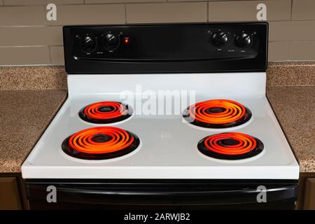 Horizontale Aufnahme der Kochplatten eines elektrischen Bereichs mit allen Brennern auf hoch und leuchtend rot. Stockfoto