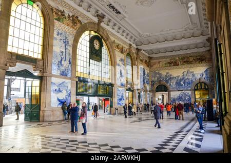 Porto, Portugal - Jan 10, 2020: Einrichtung von Sao Bento Bahnhof mit typischen Azulejo Kacheln. Typisch portugiesischen Kacheln Azulejos, der Bahnhof ist UNESCO-Weltkulturerbe. Die Leute in der Halle. Stockfoto