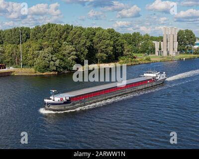 Die Cetera, ein niederländischer River Barge, der den Nordseekanal entlang der Velsertunnel-Belüftungstürme an der Nordbank führt. Stockfoto