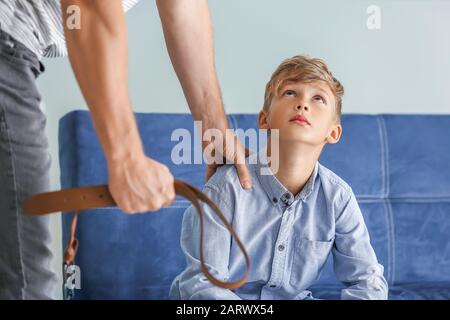 Mann bedroht seinen kleinen Sohn zu Hause. Konzept der körperlichen Bestrafung Stockfoto