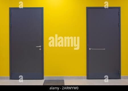 Zwei graue Türen schlossen an der gelben Wand Stockfoto
