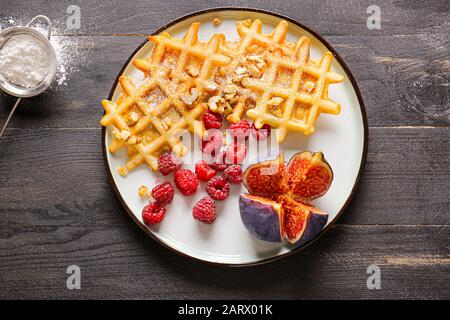 Teller mit leckeren Waffeln, Beeren und Feigen auf dem Tisch Stockfoto