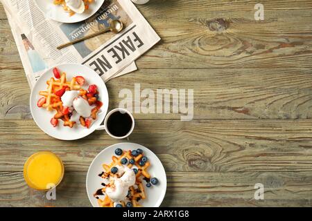 Teller mit leckeren Waffeln, Beeren und Eis auf Holztisch Stockfoto
