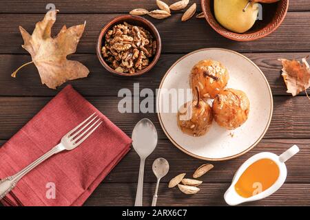 Süß gekochte Birnen mit Nüssen und Honig auf Holztisch Stockfoto