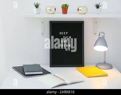 Brett mit Motivationssatz am Arbeitsplatz im Innenbereich Stockfoto