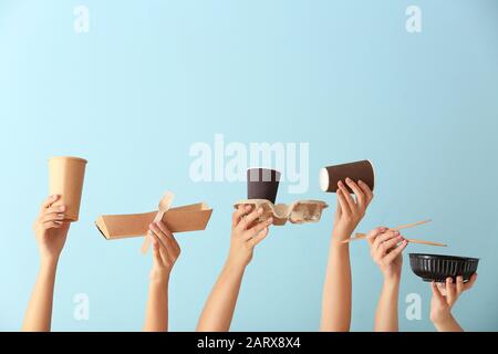Viele Hände mit Essensbehältern, Besteck und Tassen auf Farbhintergrund Stockfoto