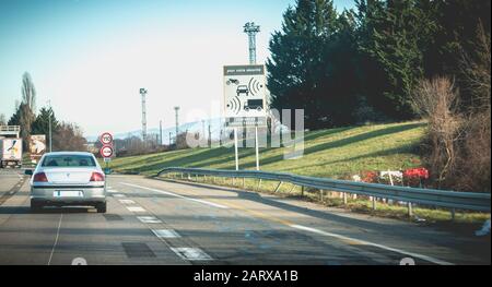 Autobahn A36 in der Nähe von Mulhouse, Frankreich - 25. Dezember 2017: Auto vor einem Straßenschild, das auf das Vorhandensein von Radargeräten für die Geschwindigkeitskontrolle hinweist. Für Ihren Stockfoto